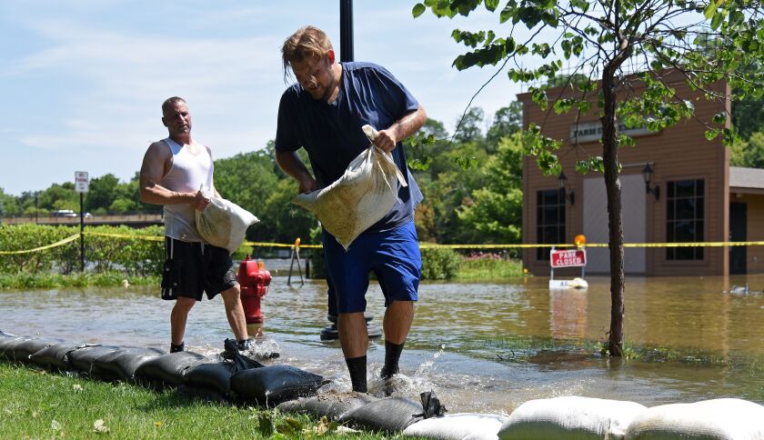 Tom McCleary, right, and Ray Robarge put another layer of sandbags on their way after Wednesday night’s rain raised the water level to a new high point for the week on La Fox River Drive Thursday. | Rick West/Daily Herald