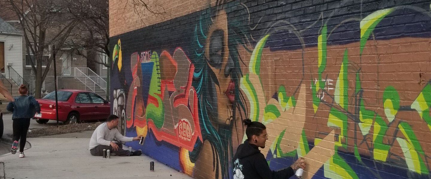 Street artists Haste (left) and Josh “Classics” work on the mural at 3389 N. Milwaukee Ave., completed in March.