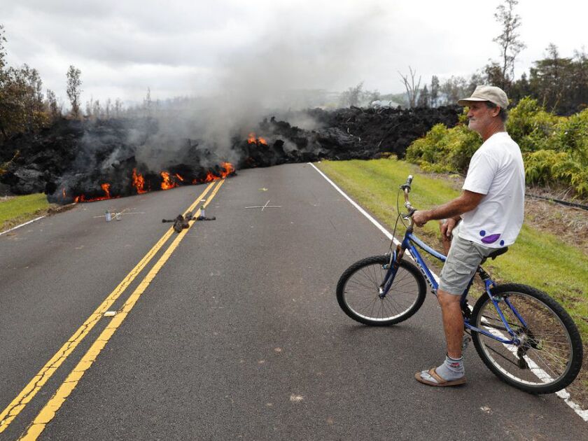 In this May 5, 2018, Leilani Estates resident Sam Knox watches the lava stretch across the road in Pahoa, Hawaii. Hawaii’s Kilauea volcano has spewed lava into the air, destroyed homes, forced residents into shelters, and agitated an otherwise cheerful, s