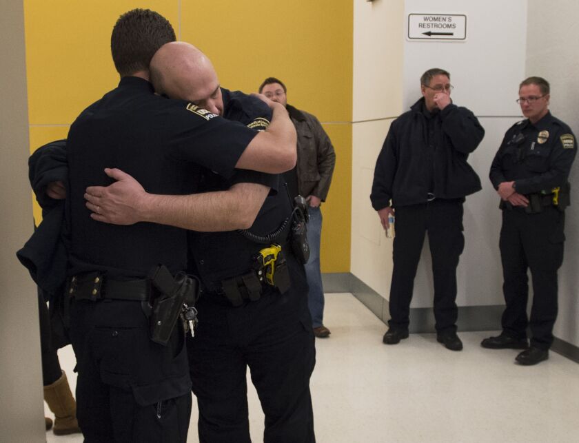 University of Colorado-Colorado Springs Lt. Clayton Garner, facing camera, hugs Lt. Marc Pino after a moment of silence for fallen officer Garrett Swasey before a college basketball game Saturday in Colorado Springs, Colo. Swasey was killed in a shooting