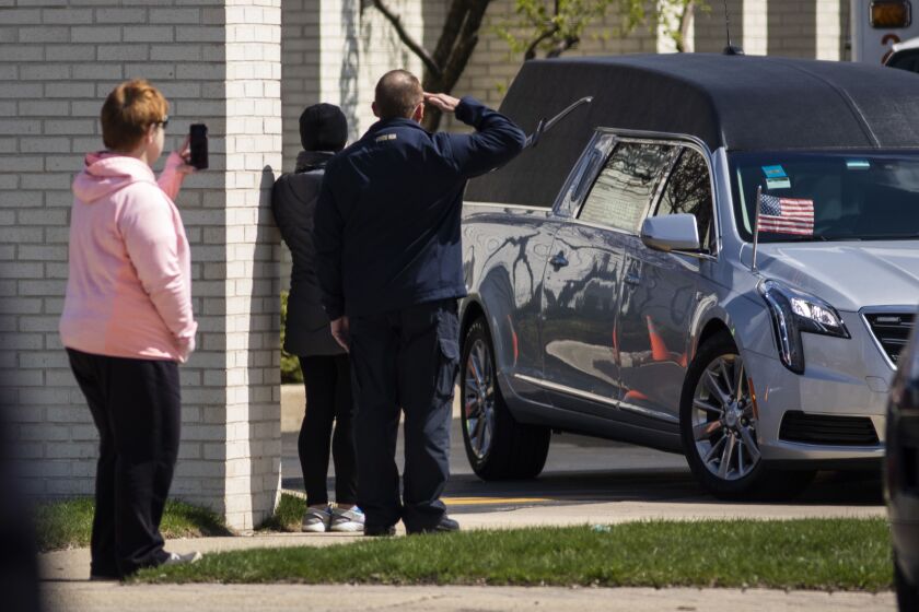 A man salutes as the hearse carrying Chicago Police Officer Officer Marco DiFranco leaves Cumberland Funeral Chapels and heads toward All Saints Catholic Cemetery & Mausoleum in Des Plaines, Thursday, April 9, 2020.