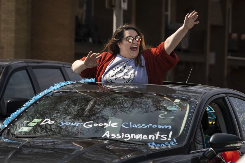 Teachers and staff at Dore Elementary School parade around the neighborhood Thursday afternoon, waving to families and children in the Southwest Side community.