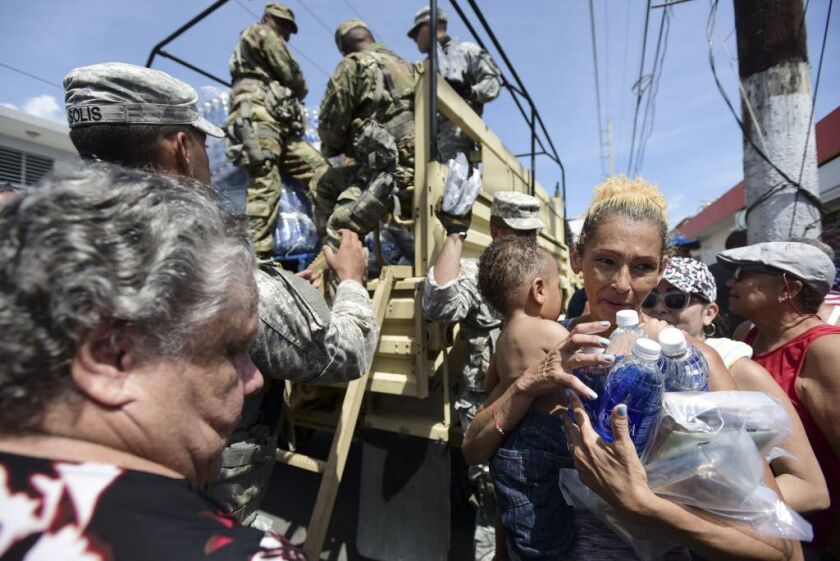 National Guard Soldiers arrive at Barrio Obrero in Santurce on Sept. 24, 2017, to distribute water and food among those affected by the passage of Hurricane Maria, in San Juan, Puerto Rico. Federal aid is racing to stem a growing humanitarian crisis in to
