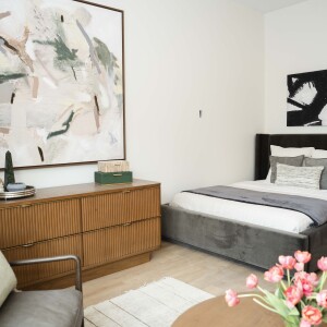 Partial view of a studio unit with a bed, dresser and seating