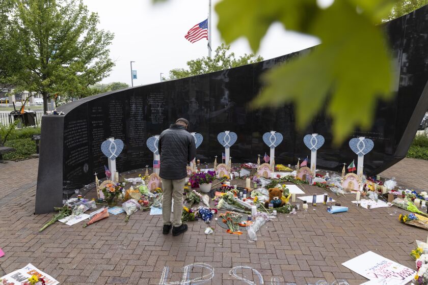 A mourner bows his head Wednesday at a memorial at Central Avenue and St. Johns Avenue for the seven people killed by shots from a rooftop with a semi-automatic rifle down on the crowd gathered Monday for Highland Park's Fourth of July parade.