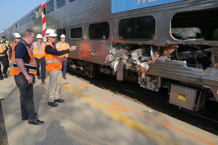 NTSB Vice Chairman Bruce Landsberg points to damage on the front car of a Metra train that struck a box truck Wednesday, fatally injuring a passenger inside the train.