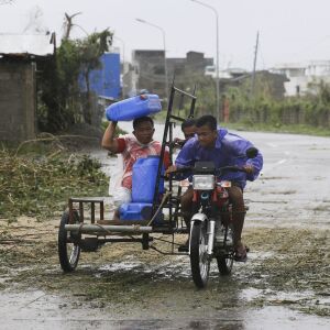 A man uses a water container to shield him from rain brought about by Typhoon Mangkhut as it barreled across Tuguegarao city, Cagayan province, northeastern Philippines, Saturday, Sept. 15, 2018. Philippine officials were assessing damage and checking on