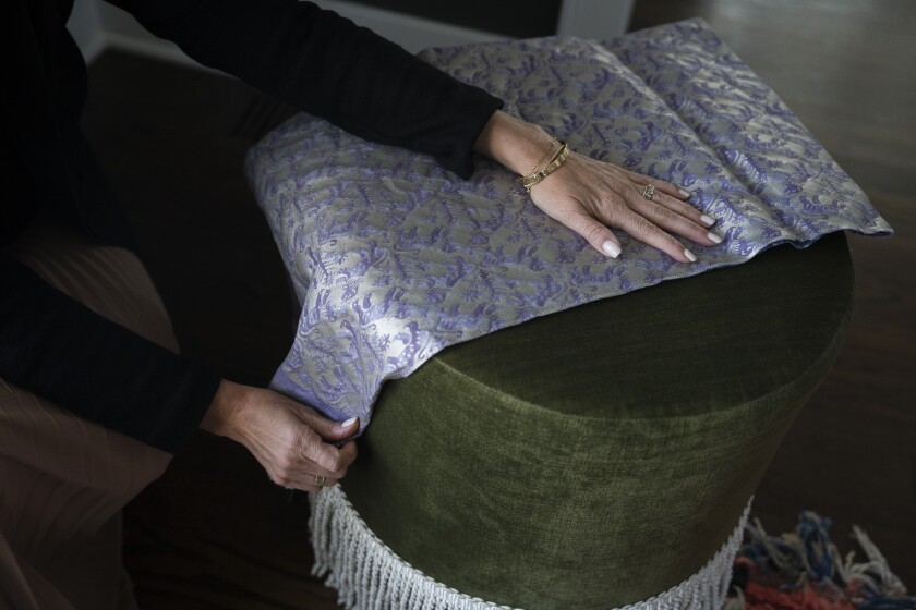 Meganne Wecker, CEO of Skyline Furniture, holds a textile sample against a velvet ottoman manufactured by the company.