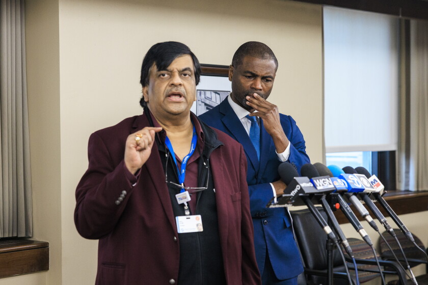 Dr. Manoj Prasad, who owns West Suburban Medical Center, speaks before a bank of microphones at the hospital in April.