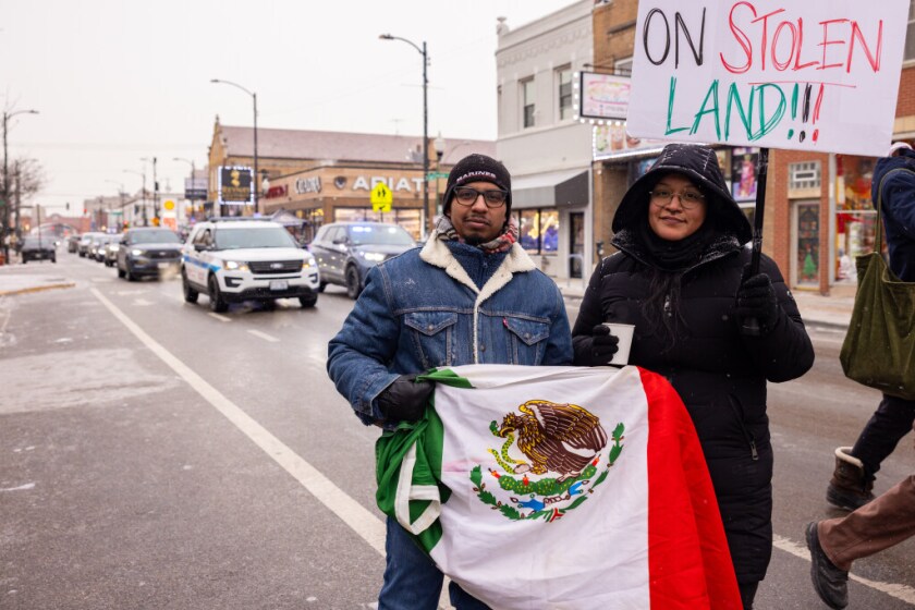 Los manifestantes Yaz Ayala (a la derecha) y Mike Hernández vinieron de Naperville para unirse a una marcha por la Calle 26 en La Villita para protestar contra los asesinatos de civiles a manos de agentes federales. Hernández, un veterano de la Marina, dijo, “Presté servicio a mi país y luché por este derecho y voy a protegerlo”.