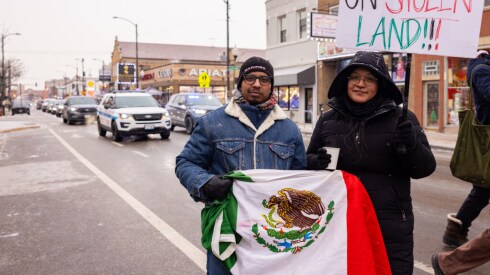 Los manifestantes Yaz Ayala (a la derecha) y Mike Hernández vinieron de Naperville para unirse a una marcha por la Calle 26 en La Villita para protestar contra los asesinatos de civiles a manos de agentes federales. Hernández, un veterano de la Marina, dijo, “Presté servicio a mi país y luché por este derecho y voy a protegerlo”.