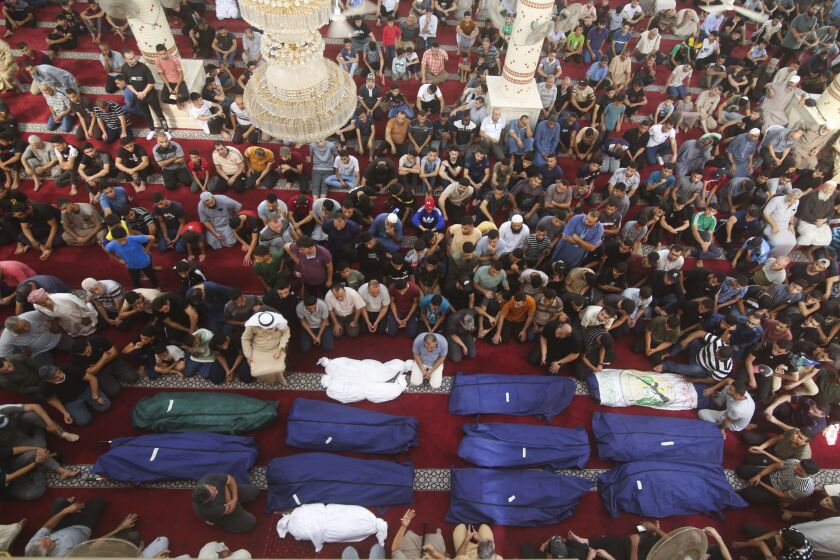 Mourners pray by the bodies of Salem Abu Quta family members, a Hamas fighter, during a funeral after they were killed in an Israeli strike on their house in Rafah refugee camp, southern Gaza Strip, on Oct. 8, 2023.