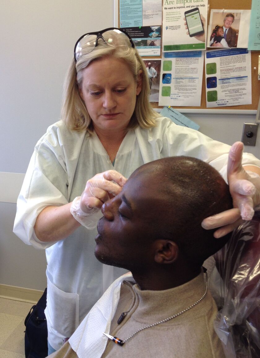 Rosie Seelaus, an anaplastologist at the Craniofacial Center, part of the University of Illinois at Chicago’s Hospital & Health Sciences System, helps to create a prosthetic for patient Victor Chukwueke, a Nigerian medical student who lost part of his