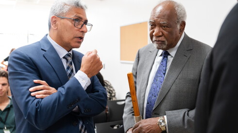 City Colleges of Chicago Chancellor Juan Salgado, in a blue suit, speaks to U.S. Rep. Danny Davis, in a dark gray suit.