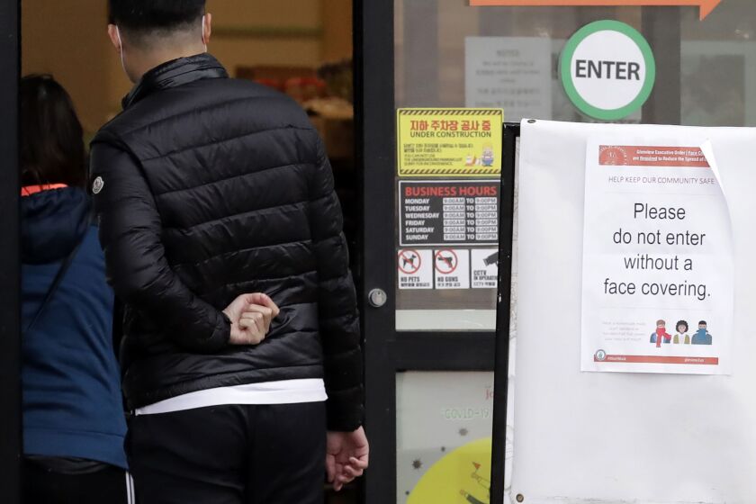 A sign requesting that customers wear a face covering is posted outside of a grocery store during the coronavirus outbreak in Glenview last month.