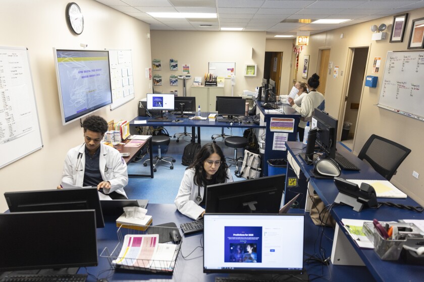 Workers at CommunityHealth wear white coats as they type into computers.