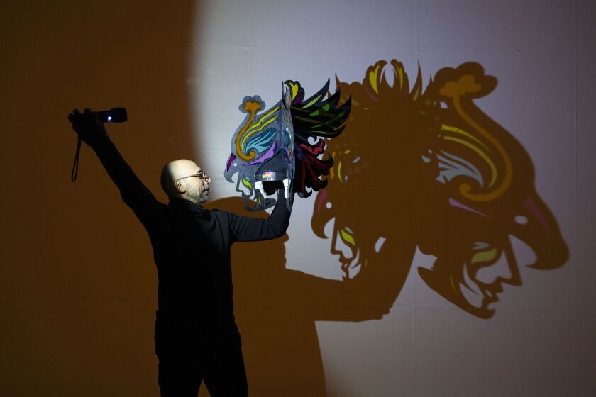 Hamid Rahmanian, creator, director and designer of “Song of the North,” a show that combines shadow puppetry and projected animation, shines a light on a hat that will be used in the show at Studebaker Theater in the Loop, Tuesday, Jan. 16, 2024. The show tells the love story of Manijeh and Bijan from ancient Persia through hundreds of handmade puppets. | Pat Nabong/Sun-Times