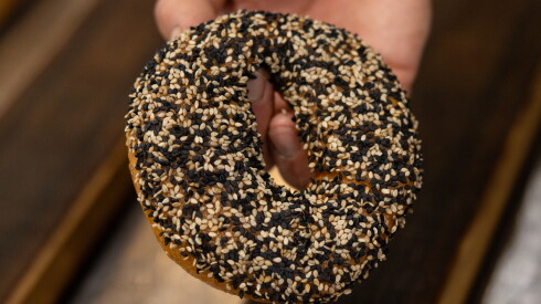 Chef and owner Felix Zepeda tops a red mole bagel with sesame at Rosca Bagels in Pilsen on the Southwest Side, Monday, June 1, 2026.