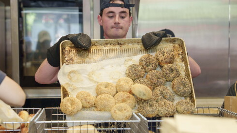 A worker places bagels into a basket at PopUp Bagels in Lincoln Park, Saturday, May 30, 2026.