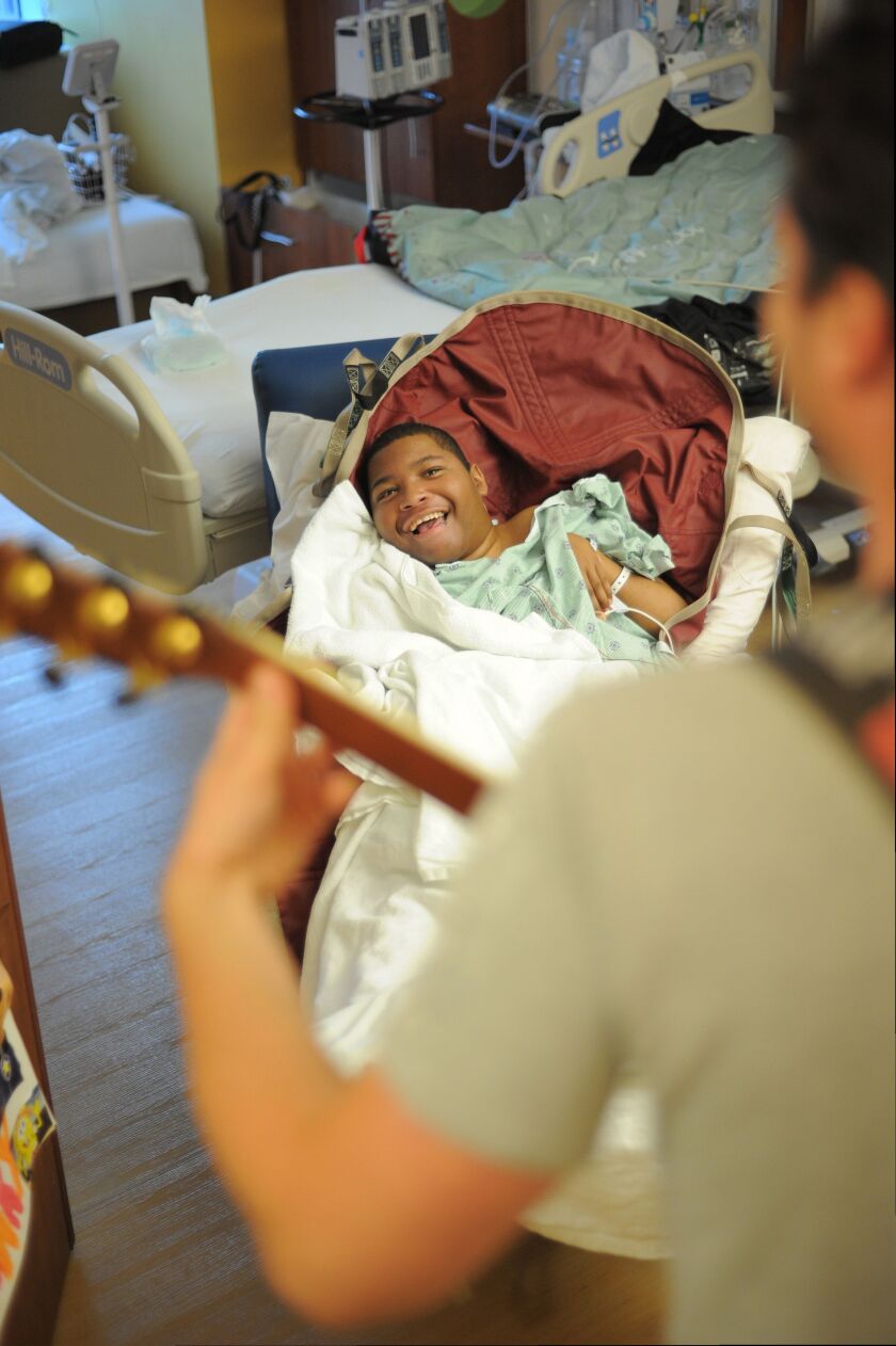 Xavier Jones (14) patient at Ann & Robert H. Lurie Children’s Hospital in Chicago reacts as he listens to the performance by volunteer musician Phil Fensel