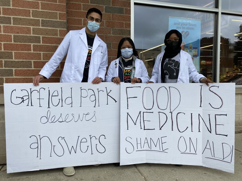 From left, Rush Medical College students Rohan Luhar, Marissa Pharos and Sadiyya Ingawa pose with handmade signs outside Aldi Headquarters at California Ave. and Granville Ave. Thursday, Oct. 28, 2021
