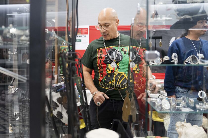 Manuel Corona, Sr., founder of Khepra Jewelers, arranges his booth during a bazaar to celebrate the first day of Kwanzaa at Malcolm X College in the Near West Side, Tuesday, Dec. 26, 2023.