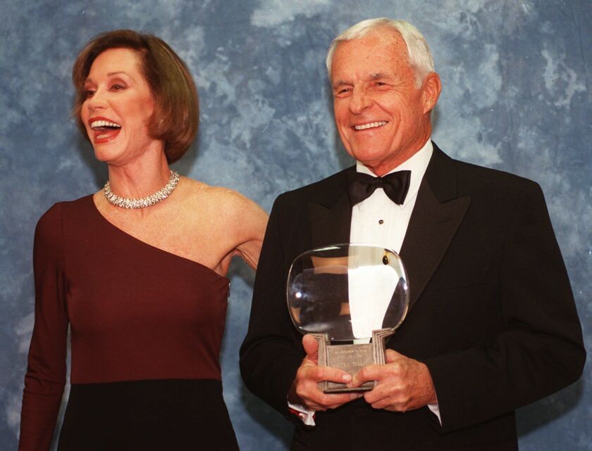 In this Saturday, Nov. 1, 1997, file photo, Television executive Grant Tinker holds up his Hall of Fame award alongside his ex-wife Mary Tyler Moore at the Academy of Television Arts & Sciences’ 13th Annual Hall of Fame induction ceremonies in the Nor