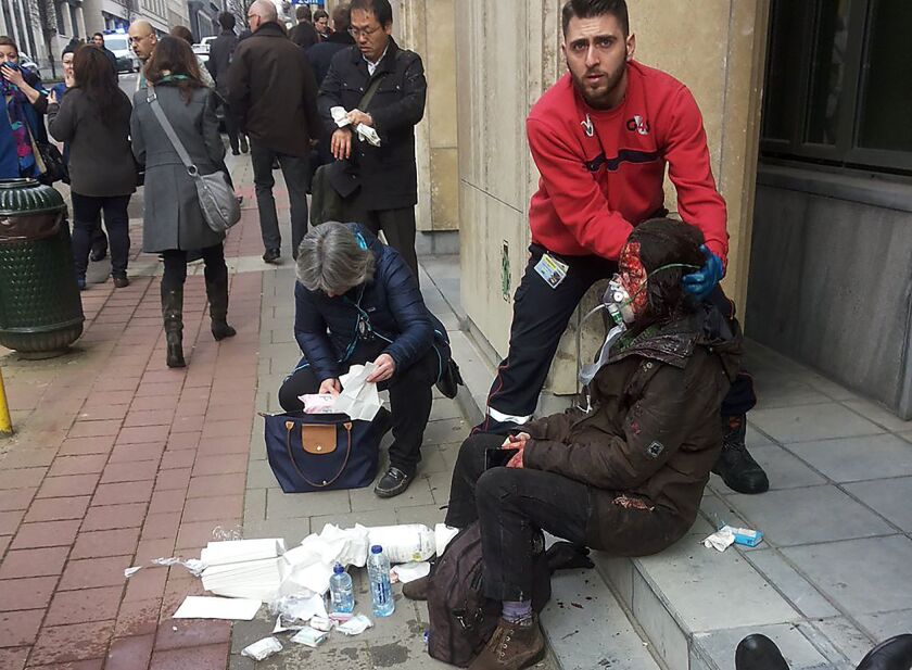 A private security guard helps a wounded women outside the Maalbeek metro station in Brussels. | Michael Villa /AFP/Getty Images