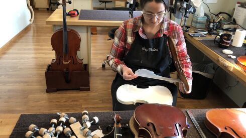 Aubrey Alexander, a violin maker at Sapp Violins in Batavia, uses a plastic liner and counterform to keep the top plate of a violin stable while she works on it. She also fishes. “Pretty much all I do is make violins, and I fish and make coffee,” she said.