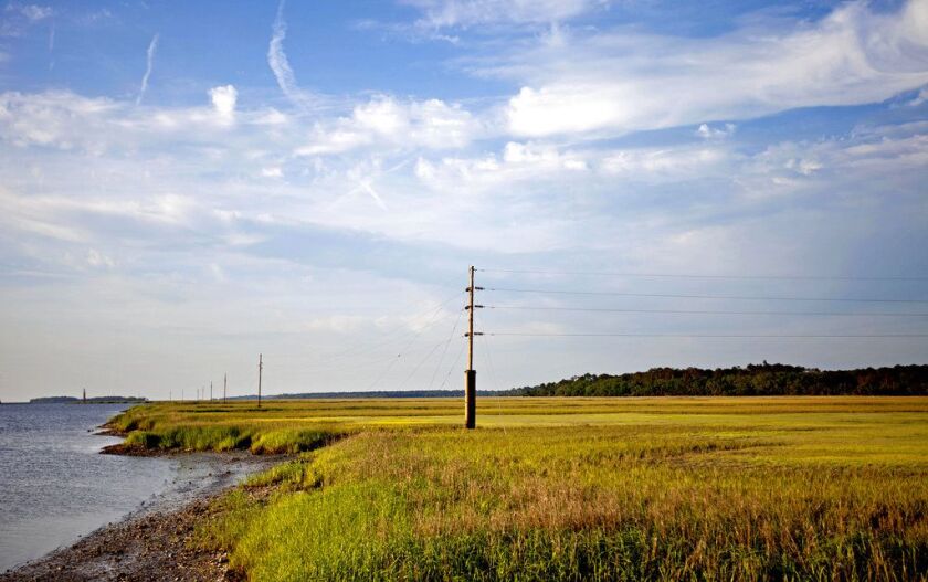 A utility pole stands in the middle of a marsh at sunset on Sapelo Island, Ga., a Gullah-Geechee community. A tight-knit community of slave descendants on the South Carolina coast is used to riding out big storms, from a storm that killed an estimated 2,0