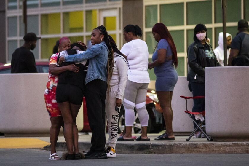 Mourners hug and cry as hundreds gather in the parking lot of Stroger Hospital after a 40-year-old man was shot to death on the West Side on Memorial Day.