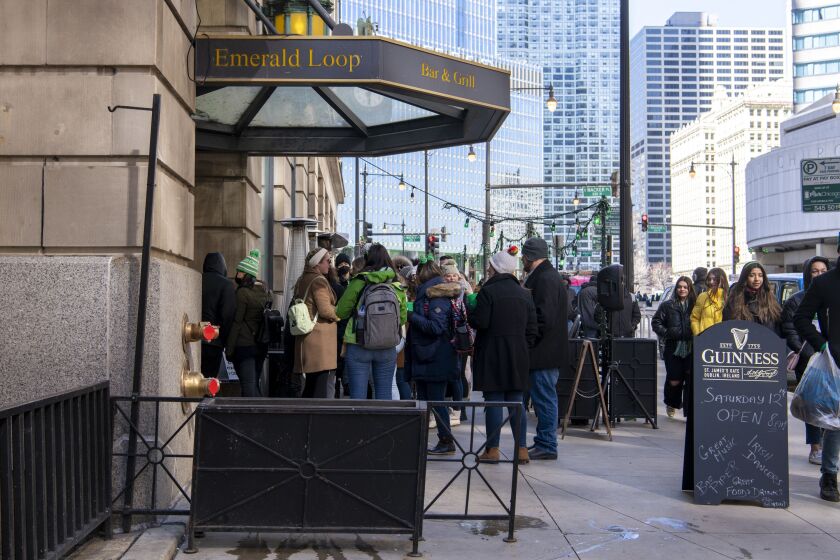 Dozens of people line up on the sidewalk outside the Emerald Loop Bar and Grill.