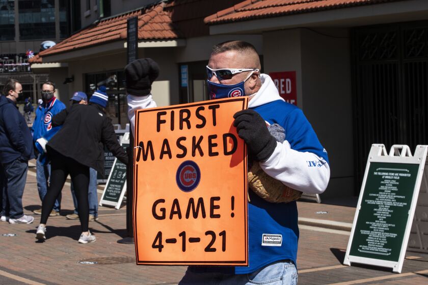 Greg Cooper, 58, of Springfield, holds a sign that says “First masked game 4-1-21” outside Wrigley Field on Opening Day.