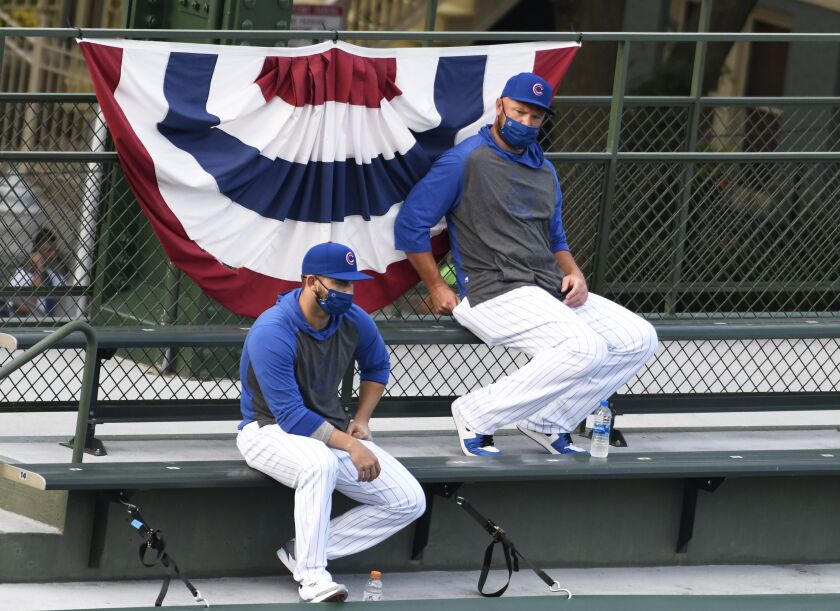 Chicago Cubs starting pitcher Jon Lester, right, watches an opening day baseball game against the Milwaukee Brewers from the bleachers during the first inning, Friday, July, 24, 2020, in Chicago.