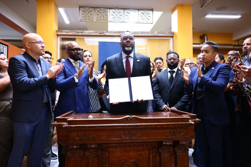 Mayor Brandon Johnson holds up the executive order he signed Monday declaring city-owned properties "ICE-free zones."