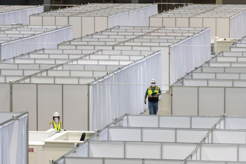 Construction workers and Illinois National Guardsmen construct medical rooms at McCormick Place’s Hall A, Friday afternoon, April 10, 2020. McCormick Place’s Hall A is being transformed into a 500 bed alternative care facility to combat the coronavirus pandemic in Chicago.