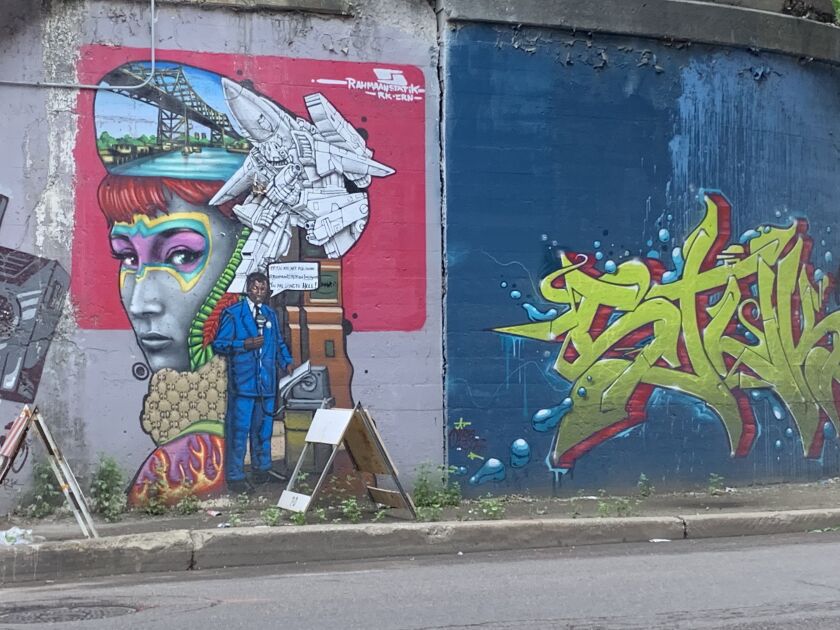 The mural (at left) by Rahmaan Statik includes images paying homage to — and having a little fun with — a downtown street preacher. “He’s told the whole city of Chicago they’re going to hell,” Statik says. As for the woman, she’s an actress in “ultimate warrior face paint.” And the bridge is modeled on one nearby. Statik says, “It’s a collection of quirky stuff, essentially, there’s even a Gucci pattern in there.” At right: graffiti art by StukOne.