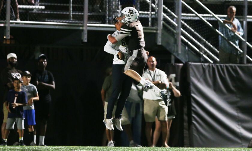 Mount Carmel head coach Jordan Lynch celebrates with Blainey Dowling (7) after one of the quarterback’s touchdown passes.
