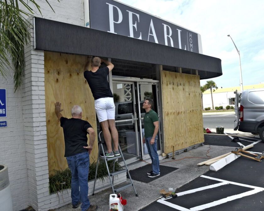 Employees Ron Weible (left), Casey Shroyer and David Tibbs, of the Pearl Home store, board up the windows of the business in advance of Hurricane Irma, on Thursday Sept. 7, 2017, in Jacksonville Beach, Florida. | Bob Mack/The Florida Times-Union via AP