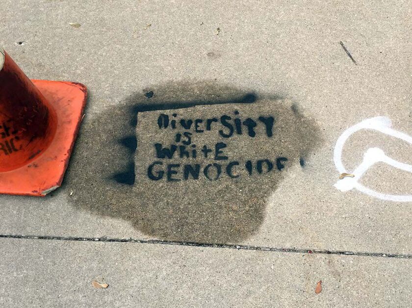 A Chicago Public Schools employee tried Sunday to scrub off the stenciled graffiti painted outside Waters Elementary School at Sunnyside and Campbell. | Sun-Times Staff photo