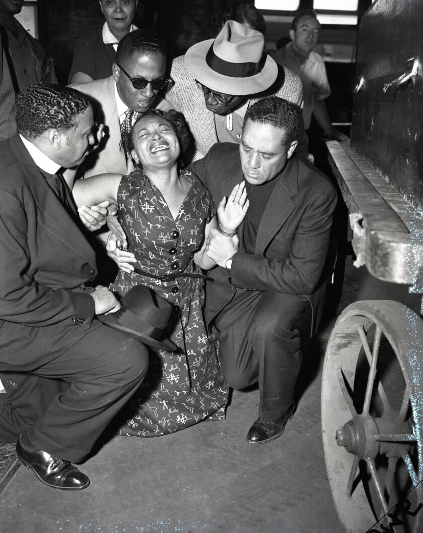 Mamie Till-Mobley kneels in prayer beside the casket of her son Emmett Till after it arrived in Chicago from Mississippi.