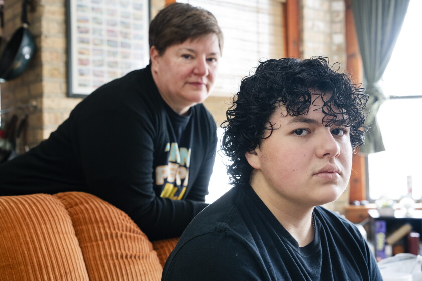 Ben Garcia sits in a chair and his mom stands behind him.