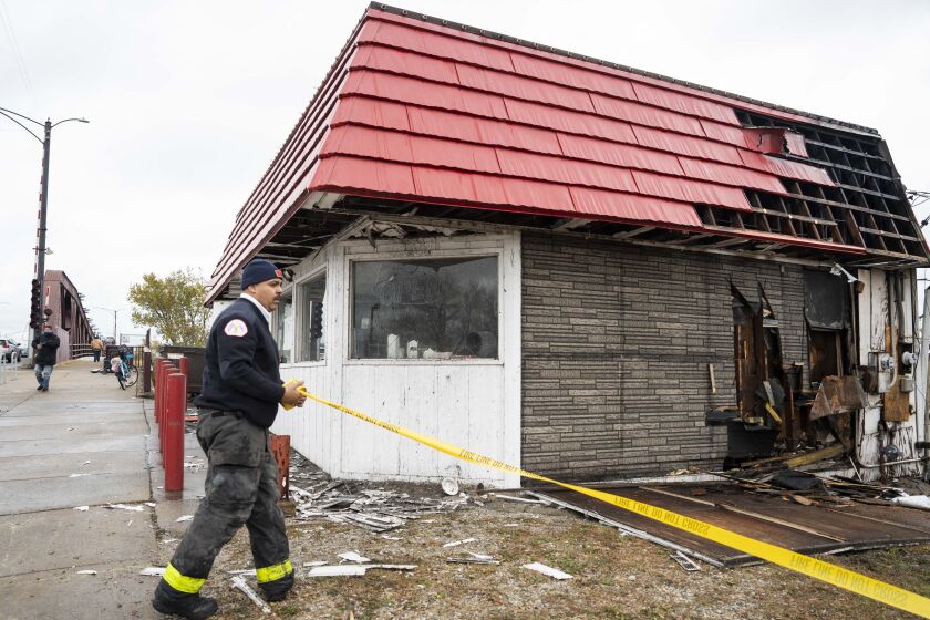 A member of the Chicago Fire Department places yellow tape around Calumet Fisheries on the Southeast Side after a fire had been extinguished, Tuesday, Nov. 21, 2023. | Pat Nabong/Sun-Times