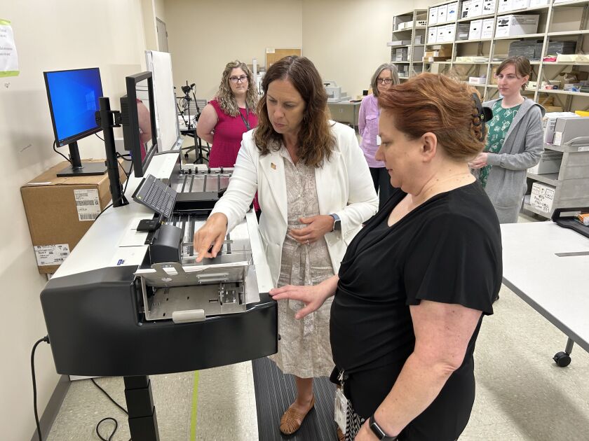 Colleen Shogan, the archivist of the United States, during a visit to the Obama Presidential Library in Hoffman Estates, with a staff member, looking at a high-speed scanner processing documents from the Obama administration.