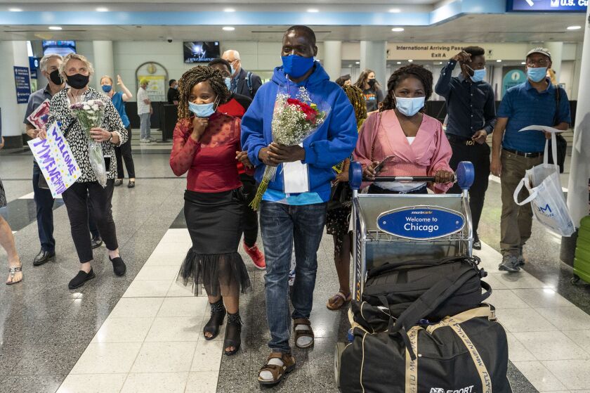 Mwenebatu Mwenemkaba, center, walks with his wife Mapenzi Mweniake, third from right, out of O’Hare International Airport’s Terminal 5, Wednesday.