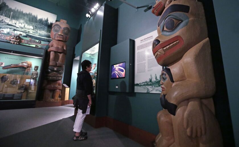 A visitor stands among totem poles as she watches a video as part of Hall of the North American Indian exhibit, at the Peabody Museum of Archaeology & Ethnology at Harvard University in Cambridge, Mass. The Peabody, one of the oldest and largest museu