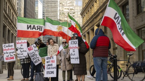 A group of protestors holding Iranian flags stands on a street in Chicago.