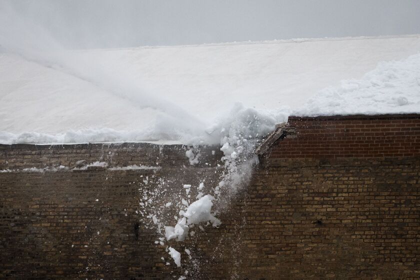 Chicago Fire Department firefighters spray water on the roof of the Aragon Ballroom to knock loose at least a foot snow that had accumulated and damaged a brick wall on the North Side building Tuesday.