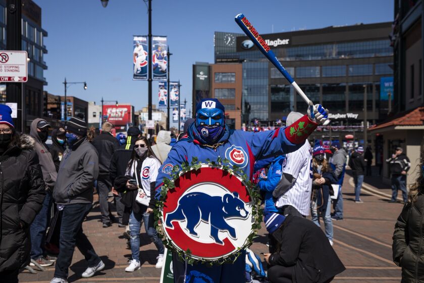 A group of Cubs fans, including Roberto Ramos, 56, of Norwood Park, wearing full team attire and a bright blue face mask, walk outside Wrigley Field on Opening Day.