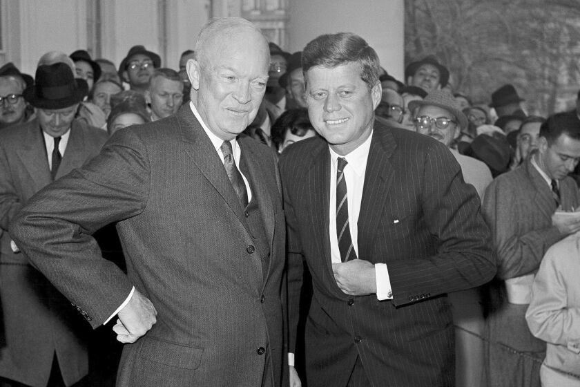 President Dwight Eisenhower poses with President-elect John F. Kennedy at the White House in Washington, before a private conference in 1960.